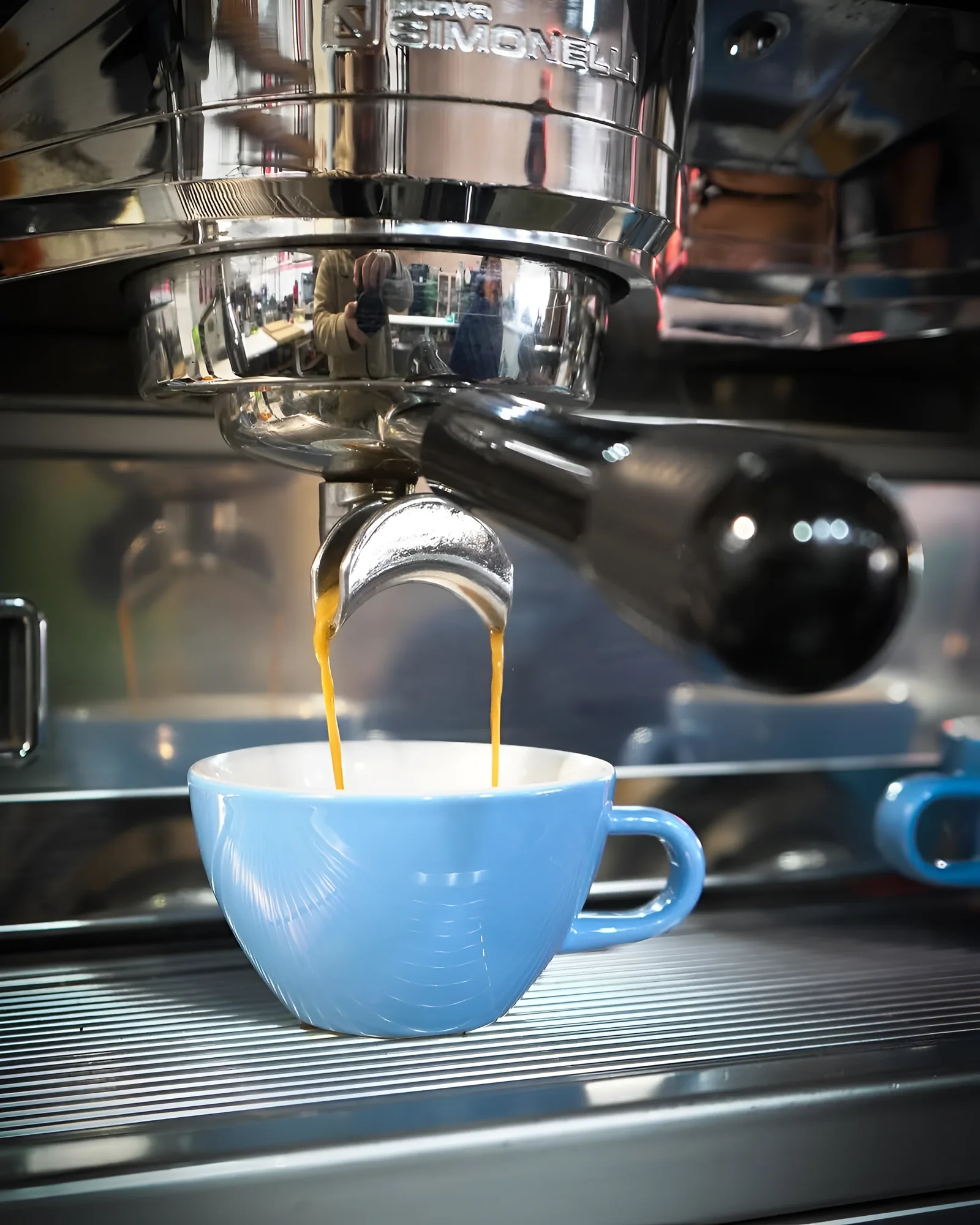 Espresso cayendo de la máquina en una taza azul