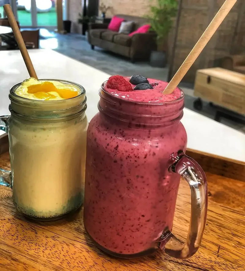 Dos smoothies en tarro de cristal, uno de mango y otro de frutos rojos